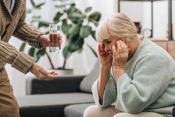 Senior gibt Glas Wasser und Pillen an alte Frau — Stockfoto