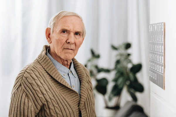 Senior man staying near calendar and looking at camera — Stock Photo