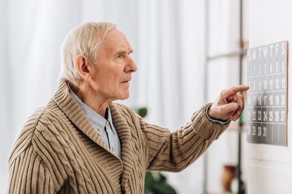 Vieil homme regardant le calendrier et se souvenant des dates — Photo de stock