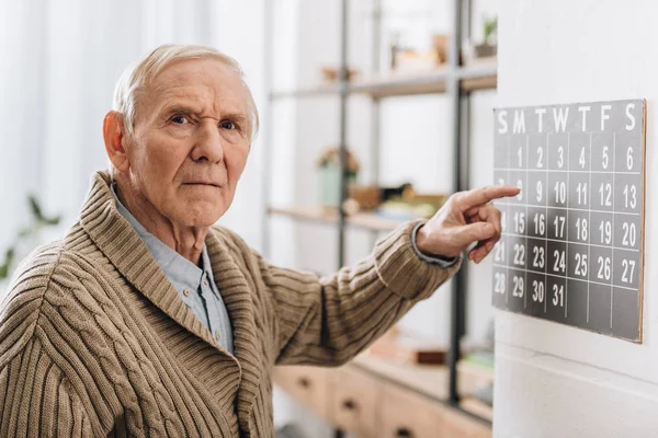 Vecchio uomo toccare il calendario guardando la fotocamera — Foto stock