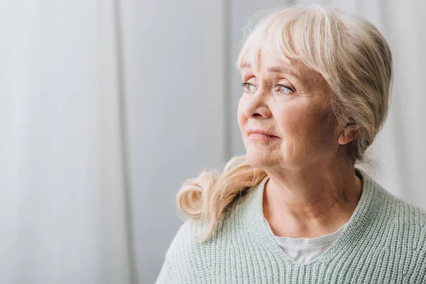 Femme âgée rêveuse aux cheveux blonds à la maison — Photo de stock