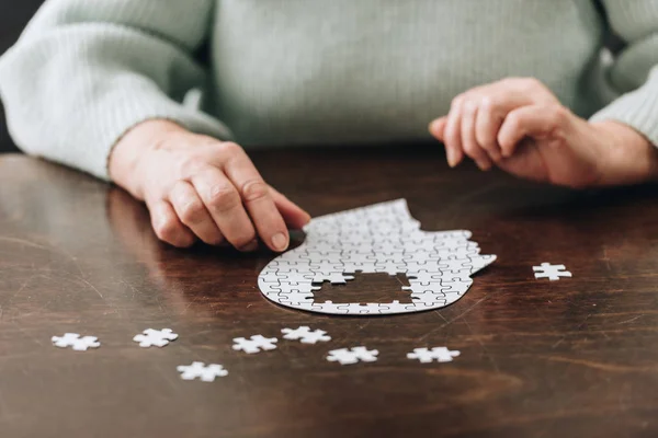 Vue recadrée de la femme âgée jouant avec des puzzles sur la table — Photo de stock