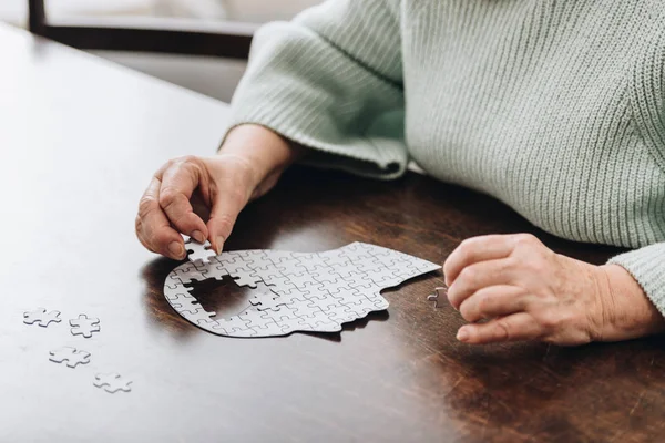 Cropped view of senior woman playing with puzzles — Stock Photo