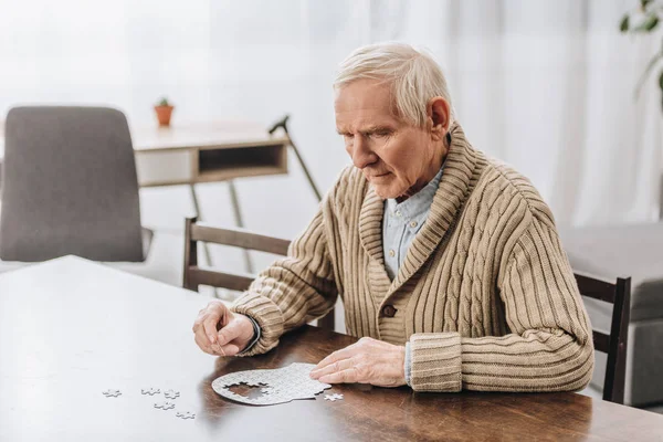Pensioner with grey hair playing with puzzles at home — Stock Photo