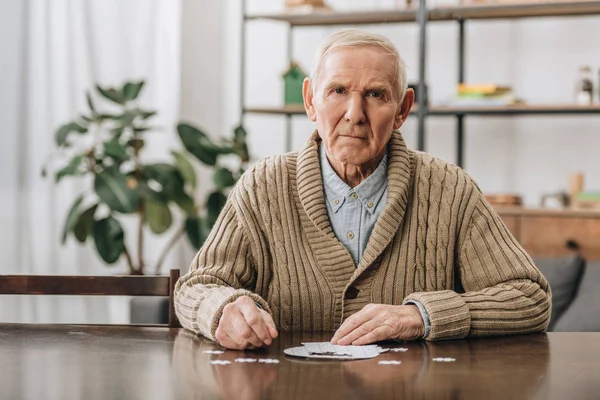 Bouleversé homme à la retraite avec les cheveux gris jouer avec des puzzles à la maison — Photo de stock