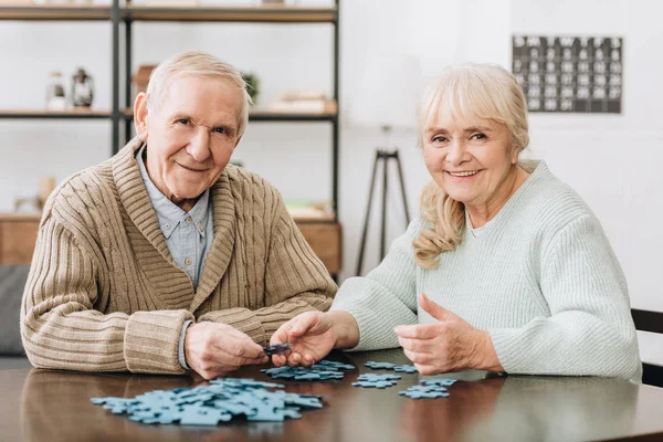 Alegre casal aposentado jogando com quebra-cabeças em casa — Fotografia de Stock