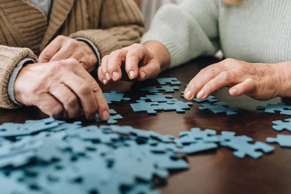 Vista cortada de casal aposentado jogando com quebra-cabeças em casa — Fotografia de Stock