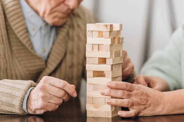 Cropped view of retired couple playing jenga game at home — Stock Photo