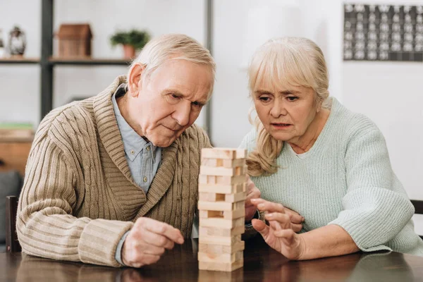 Rentnerehepaar spielt Jenga-Spiel auf Tisch — Stockfoto