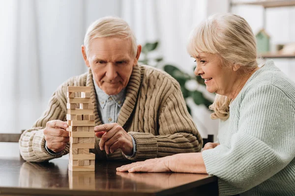 Aposentado marido e mulher jogar jenga jogo na mesa — Fotografia de Stock