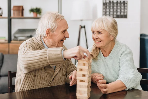 Lächelnde Rentner beim Jenga-Spiel auf dem Tisch — Stockfoto