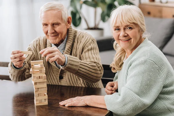 Happy pensioners playing jenga game on table — Stock Photo