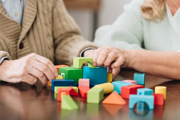 Cropped view of retired couple playing with wooden bricks on table — Stock Photo