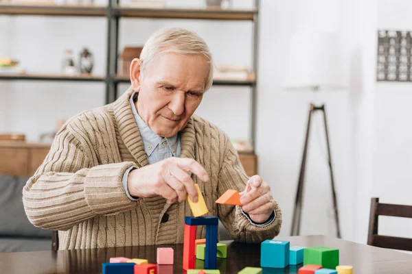 Hombre retirado jugando con juguetes de madera en casa - foto de stock