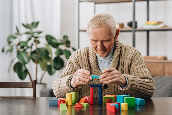 Senior spielt zu Hause mit Holzformen — Stockfoto