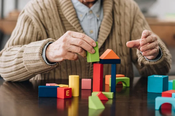 Vista cortada de homem sênior brincando com brinquedos de madeira em casa — Fotografia de Stock