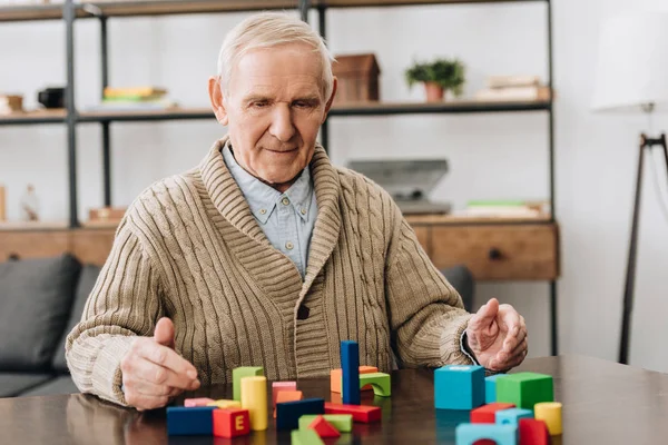 Homem sênior brincando com brinquedos de madeira na mesa — Fotografia de Stock