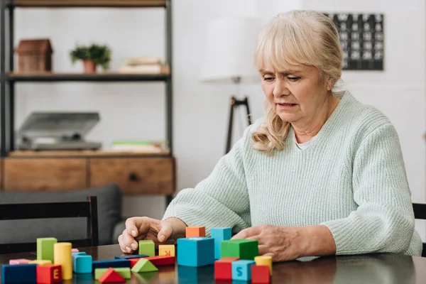 Rentnerin spielt zu Hause mit Holzspielzeug — Stockfoto