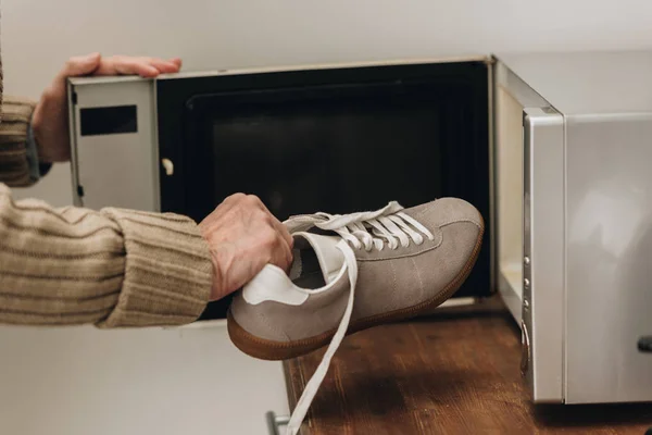 Vista ritagliata di uomo anziano mettere scarpe all'interno del forno a microonde — Foto stock