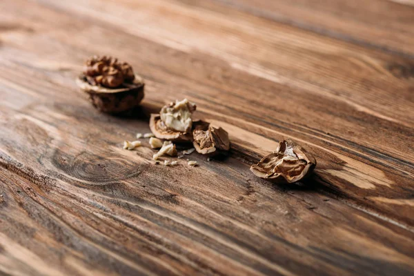 Треснувшие грецкие орехи в скорлупе ореха как символ слабоумия на деревянном столе — стоковое фото