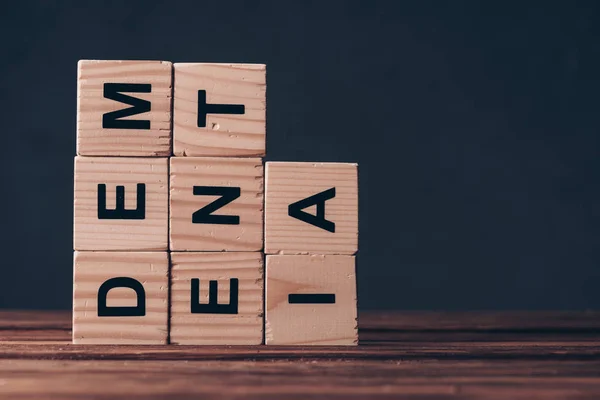 Cubes avec lettres de démence sur table en bois sur fond noir — Photo de stock