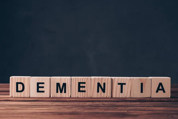 Cubes en bois avec lettres de démence sur fond noir — Photo de stock