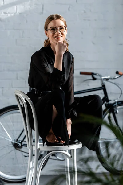 Attraktive Frau sitzt auf Stuhl und lächelt in die Kamera — Stockfoto