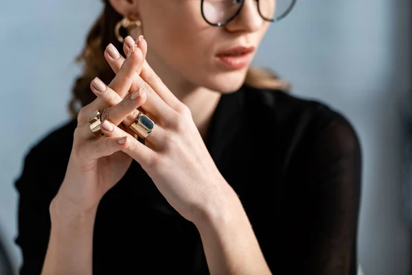 Woman in black clothes and glasses touching rings — Stock Photo