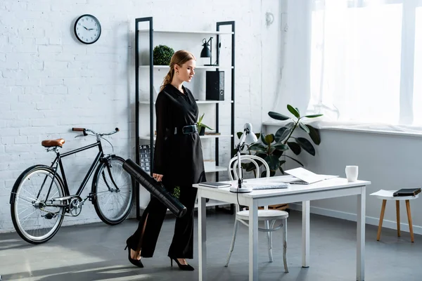 Schöne Geschäftsfrau in schwarzen Kleidern steht im Büro und schaut auf Notizbuch — Stockfoto