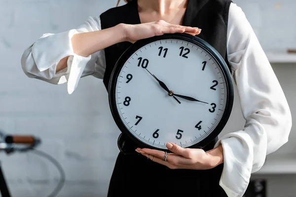 Cropped view of woman in formal wear holding clock in hands — Stock Photo