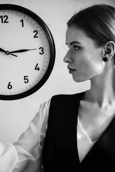 Black and white photo of woman in formal wear holding clock and looking away — Stock Photo