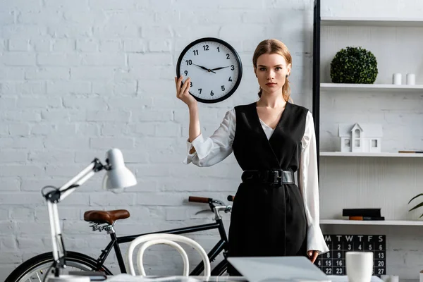 Seriöse Geschäftsfrau in formeller Kleidung hält Uhr am Arbeitsplatz — Stockfoto