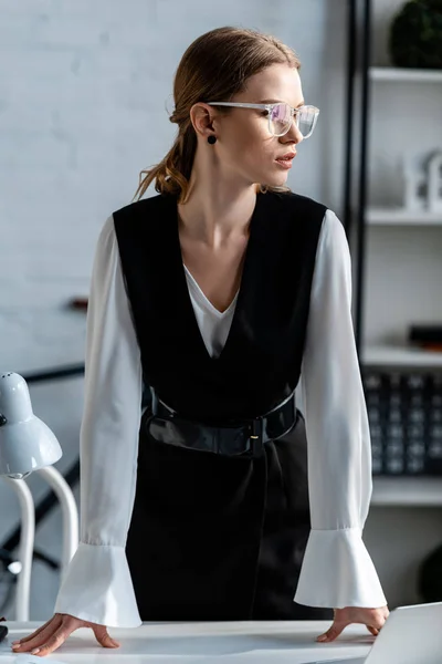 Selective focus of beautiful businesswoman in formal wear and glasses looking away — Stock Photo