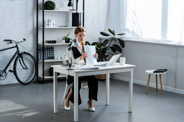 Mujer de negocios en ropa formal sentada en el escritorio de la computadora con documentos en la oficina — Stock Photo