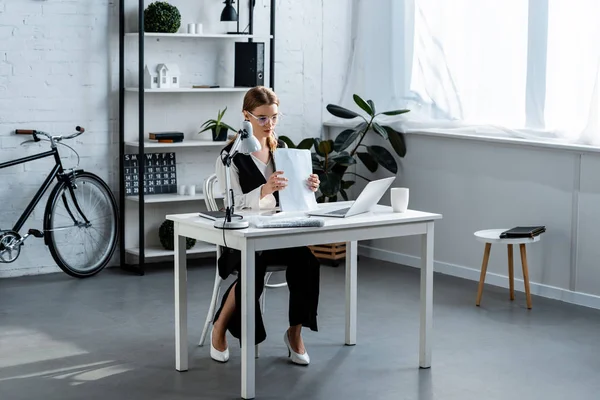 Femme d'affaires en tenue de cérémonie assise au bureau de l'ordinateur avec des documents au bureau — Photo de stock