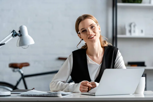 Lächelnde Geschäftsfrau in festlicher Kleidung sitzt am Computer-Schreibtisch am Arbeitsplatz — Stockfoto