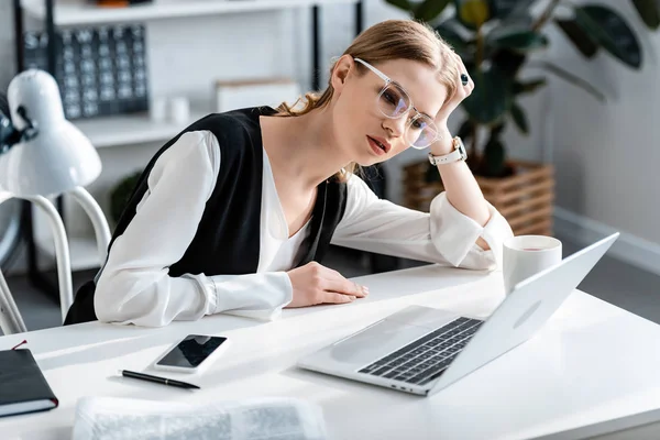 Mulher de negócios cansada em uso formal e óculos sentados na mesa de computador no local de trabalho — Fotografia de Stock