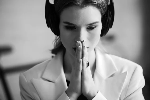 Schwarz-Weiß-Porträt einer schönen Frau mit Kopfhörern und gefalteten Händen — Stockfoto