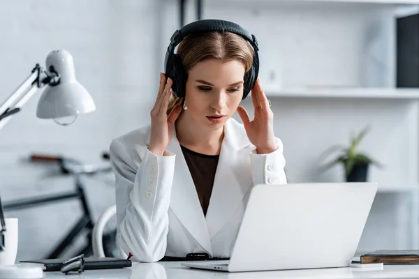 Mulher de negócios em fones de ouvido e desgaste formal sentado na mesa de computador no local de trabalho — Fotografia de Stock