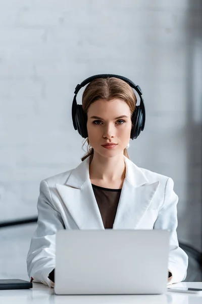 Fokussierte Geschäftsfrau mit Kopfhörern sitzt am Computertisch am Arbeitsplatz — Stockfoto