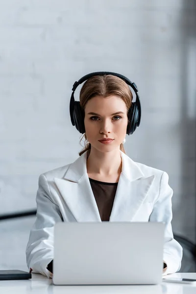 Donna d'affari concentrata in cuffie seduto alla scrivania del computer sul posto di lavoro — Foto stock