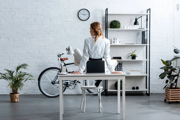 Rückansicht einer Geschäftsfrau in formeller Kleidung, die am Computer-Schreibtisch im modernen Büro sitzt — Stockfoto