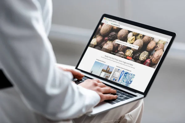 Vista recortada de la mujer que utiliza el ordenador portátil con sitio web depositphotos en la pantalla - foto de stock
