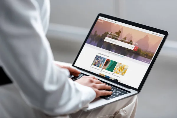 Vista cortada da mulher usando laptop com shutterstock site na tela — Fotografia de Stock