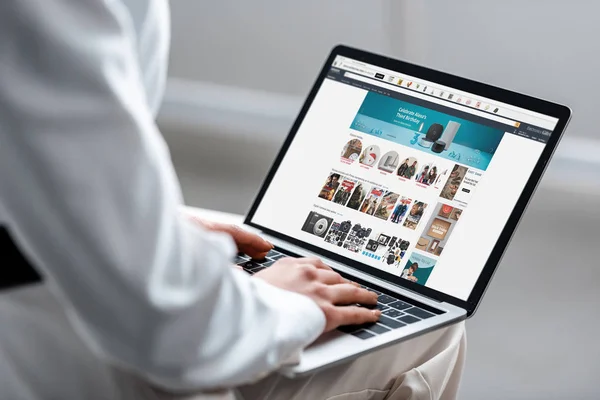 Vista ritagliata della donna utilizzando laptop con sito web amazon sullo schermo — Foto stock