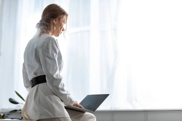 Rückansicht einer Geschäftsfrau in weißer Festkleidung mit Laptop am Arbeitsplatz mit Kopierraum — Stockfoto
