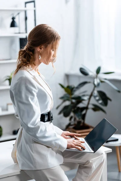 Femme d'affaires en tenue de cérémonie blanche utilisant un ordinateur portable sur le lieu de travail — Photo de stock