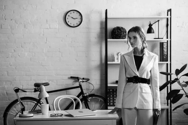 Foto in bianco e nero di seria donna d'affari in abbigliamento formale negli interni degli uffici moderni — Foto stock