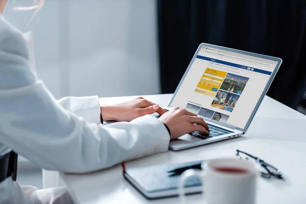 Cropped view of woman using laptop with booking website on screen at office desk — Stock Photo