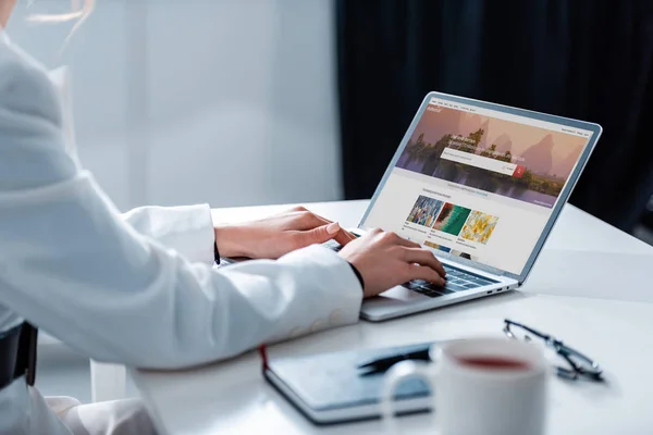 Cropped view of woman using laptop with shutterstock website on screen at office desk — Stock Photo